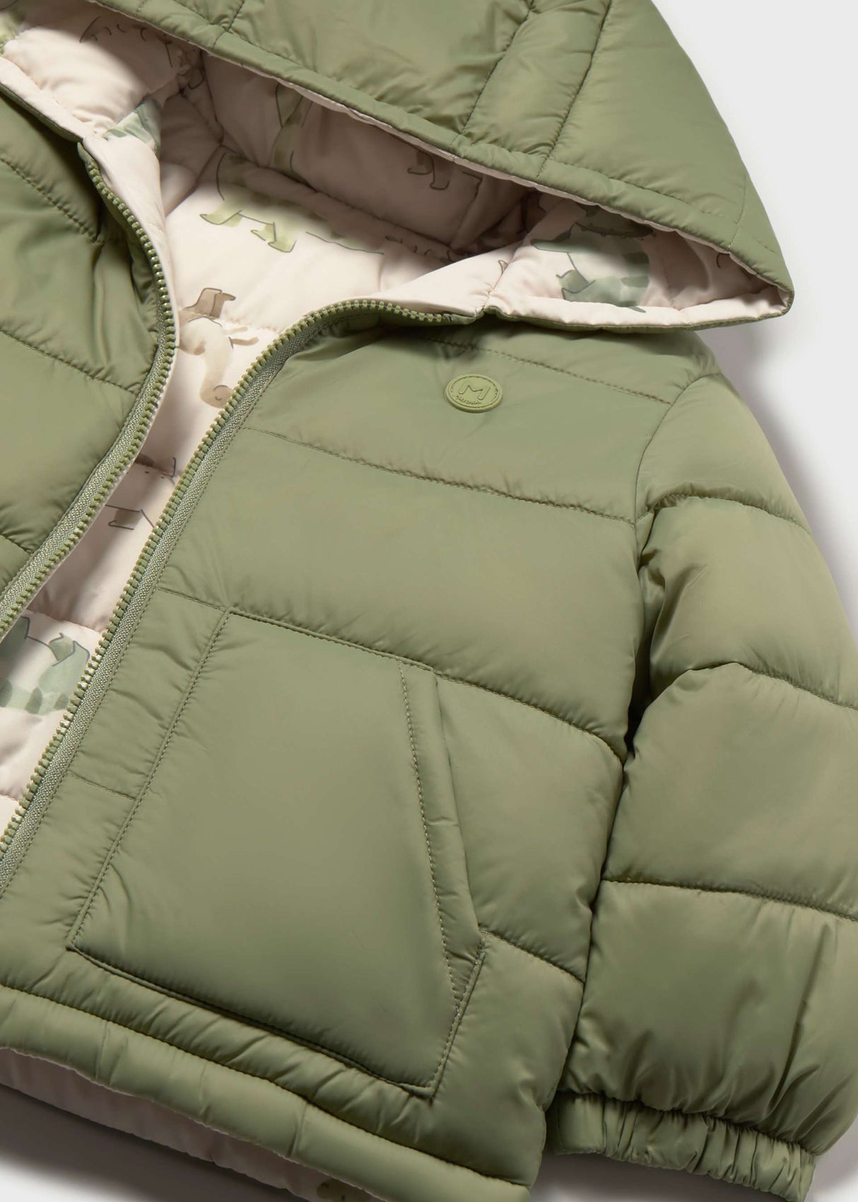 Close-up of Mayoral baby boy reversible puffer jacket showing dinosaur print lining, Olive Green side, and quilted detail.