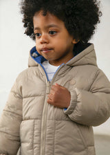 Baby boy wearing Mayoral reversible puffer jacket on the solid Taupe side for neutral winter styling.