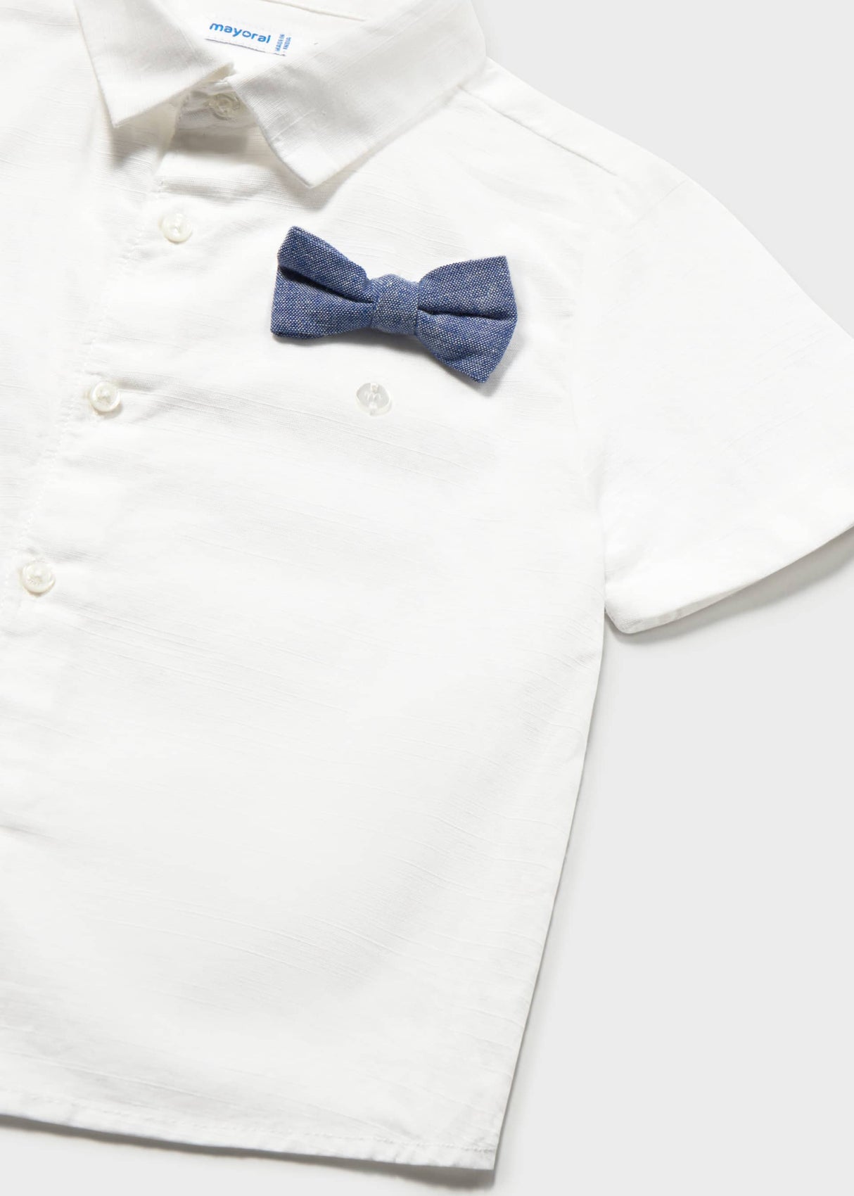 Closeup of Mayoral white short-sleeve shirt with button front and navy bow tie detail.