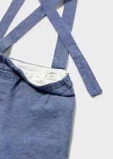 Closeup of blue Bermuda shorts with suspender straps and cotton-linen fabric detail.