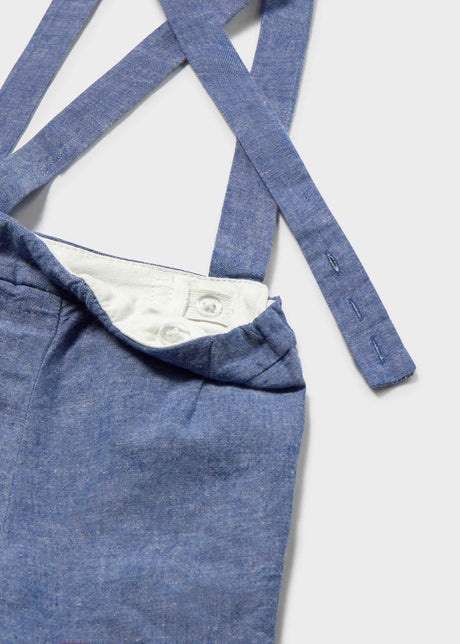 Closeup of blue Bermuda shorts with suspender straps and cotton-linen fabric detail.