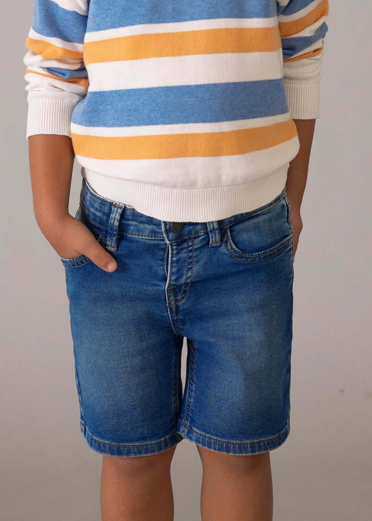 Closeup lifestyle view of Mayoral boys denim shorts showing waistband and Blue denim wash.