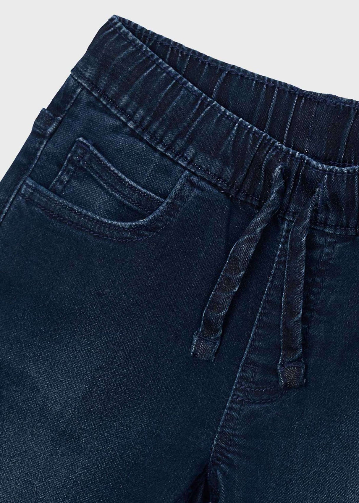 Close-up of Mayoral boys jeans showing elastic waist, drawstring-style detail, and dark denim fabric.