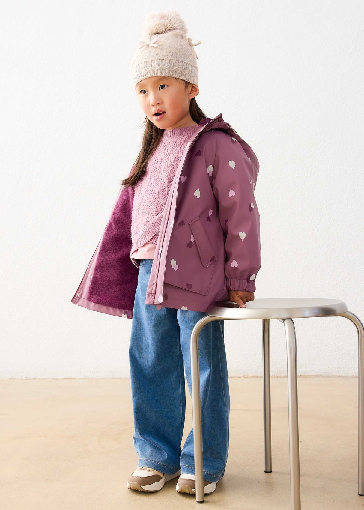 Girl wearing Mayoral Mauve heart print raincoat with hood for school and rainy-day outings.