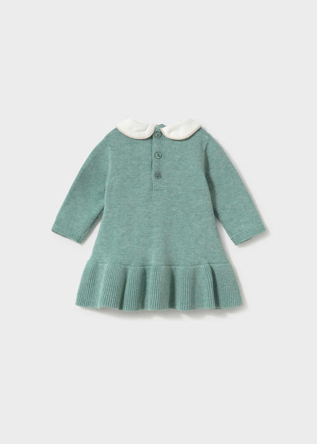 Back view of the sage green knit dress with two buttons at the neck and a ribbed ruffle hem